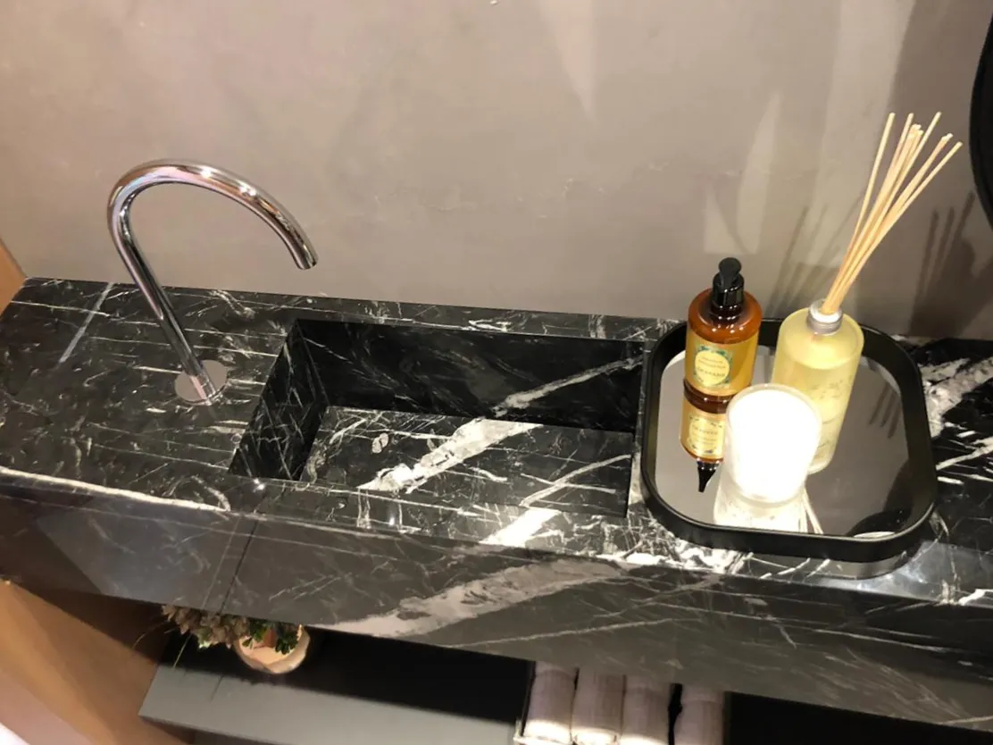 Bancada de mármore preto veiado de branco, com cuba embutida e torneira cromada