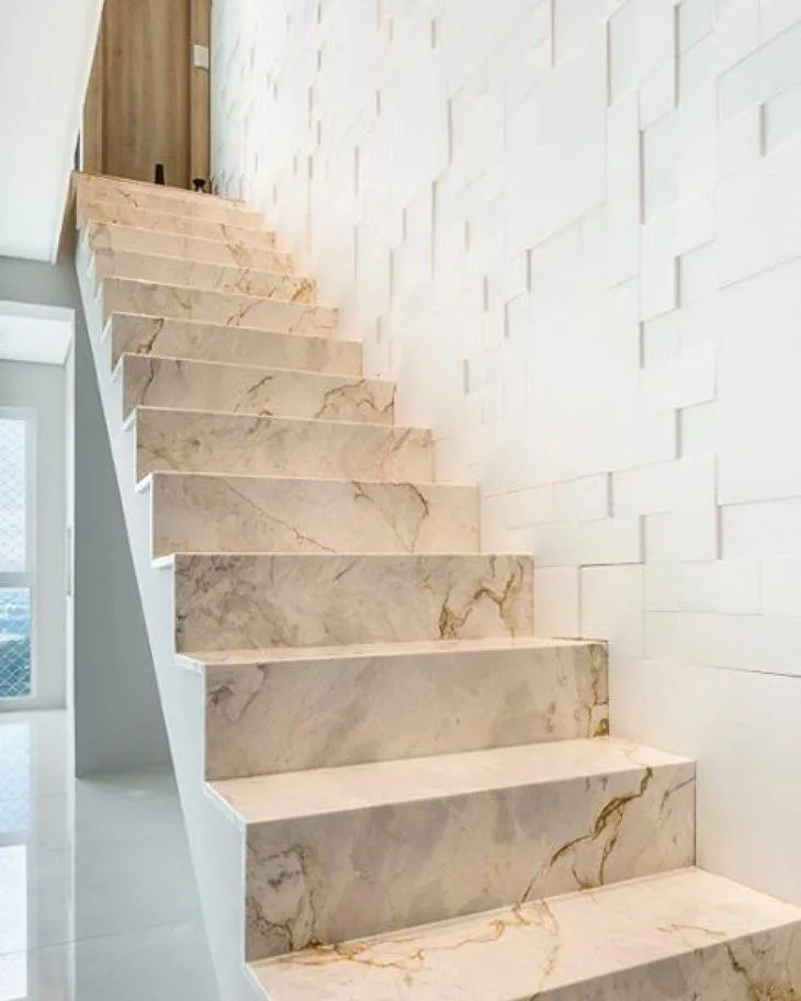 Escada de degraus em mármore bege veiado junto a parede de revestimento branco