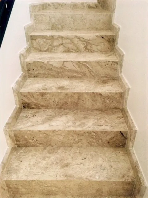 Lance de escada com degraus e espelhos em travertino, em vão de parede clara