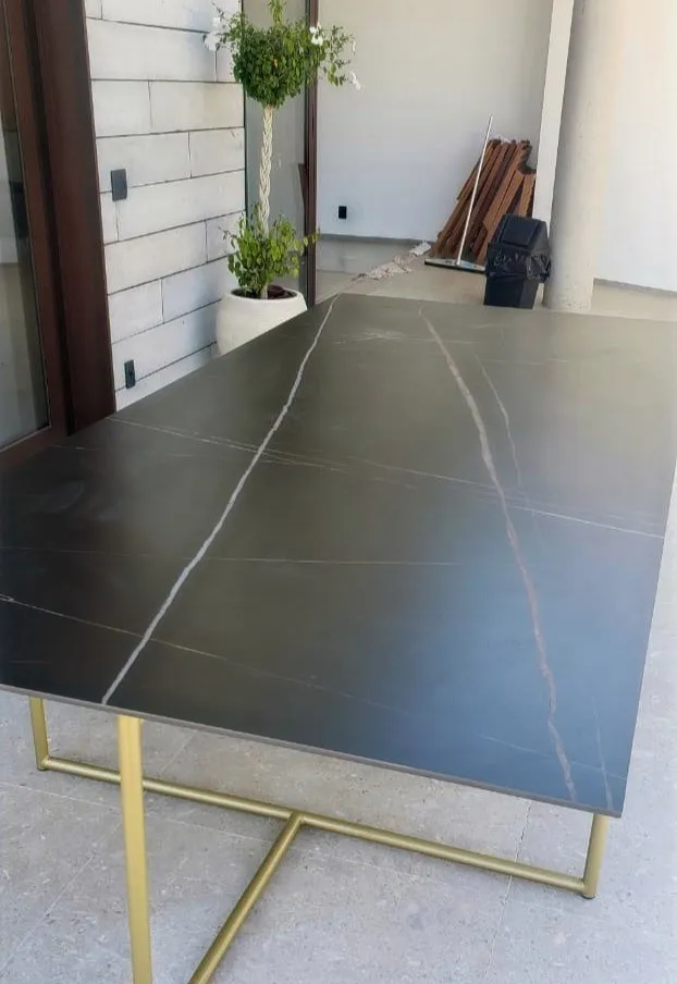 Mesa de tampo em pedra escura veiada sobre base metálica dourada