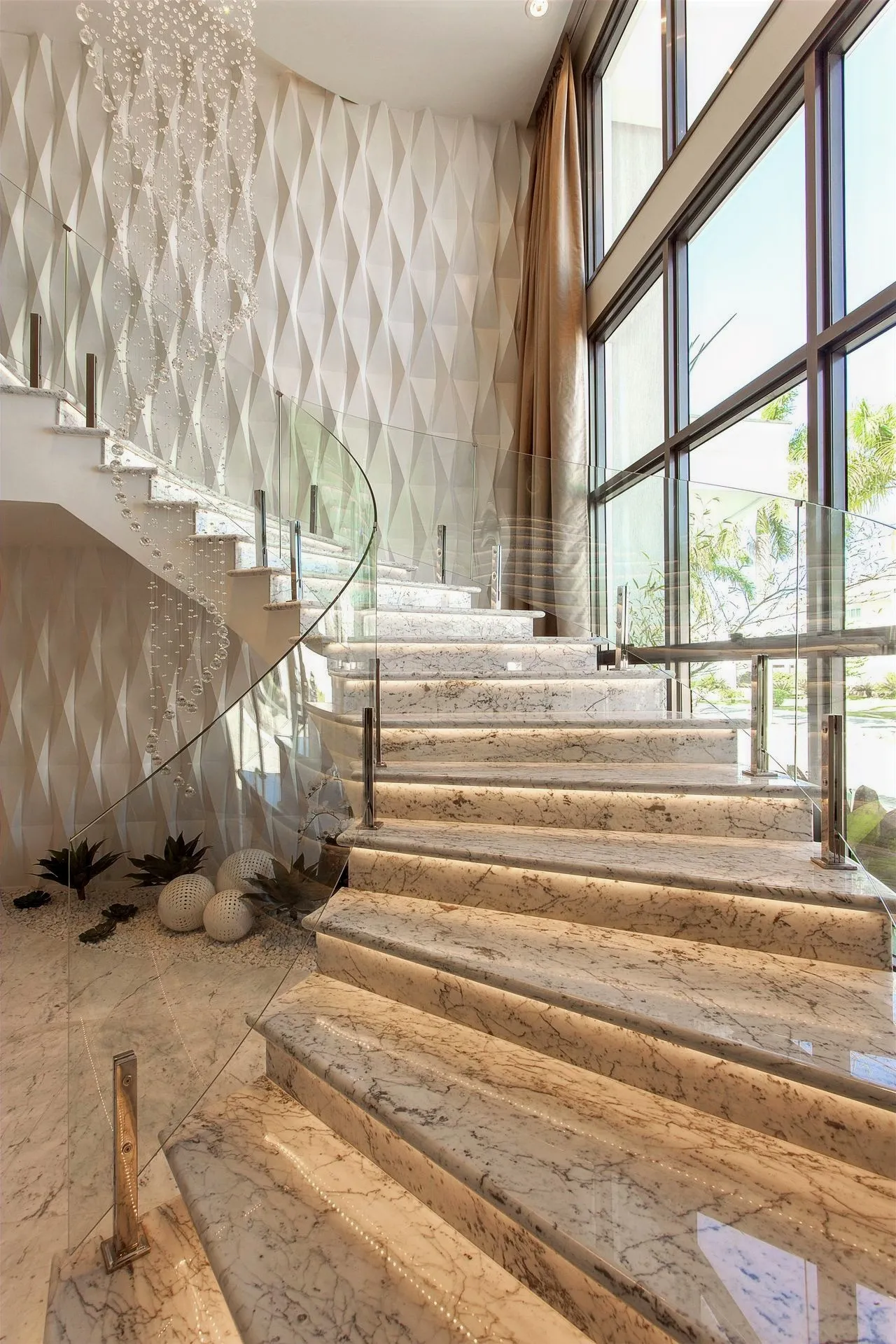 Escada de travertino com guarda-corpo de vidro em sala de pé-direito duplo